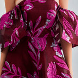 Zelene Gown in red with a dramatic silhouette and intricate floral accents